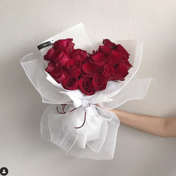 Bouquet of red roses wrapped in white paper and mesh
