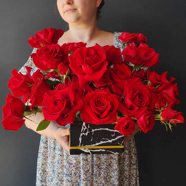 Large bouquet of red roses in a black box with a gold band