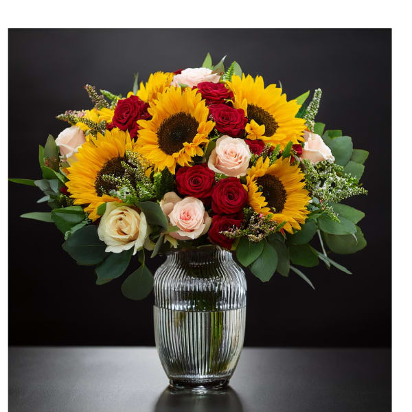 Bouquet of sunflowers and roses in a clear glass vase