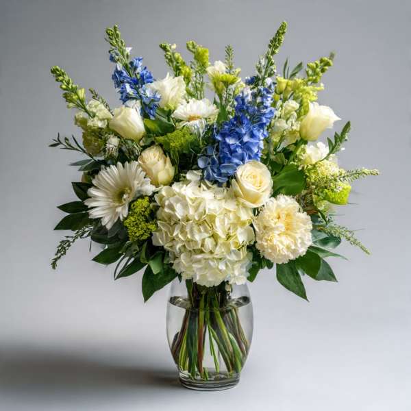 White and blue mixed bouquet in a clear glass vase