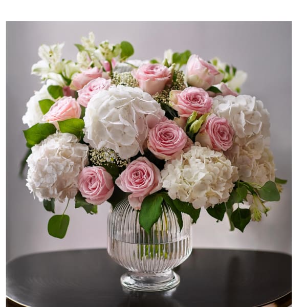 Pink roses and white hydrangeas arranged in a clear glass vase