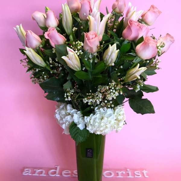 Pink roses and white lilies in a tall green vase