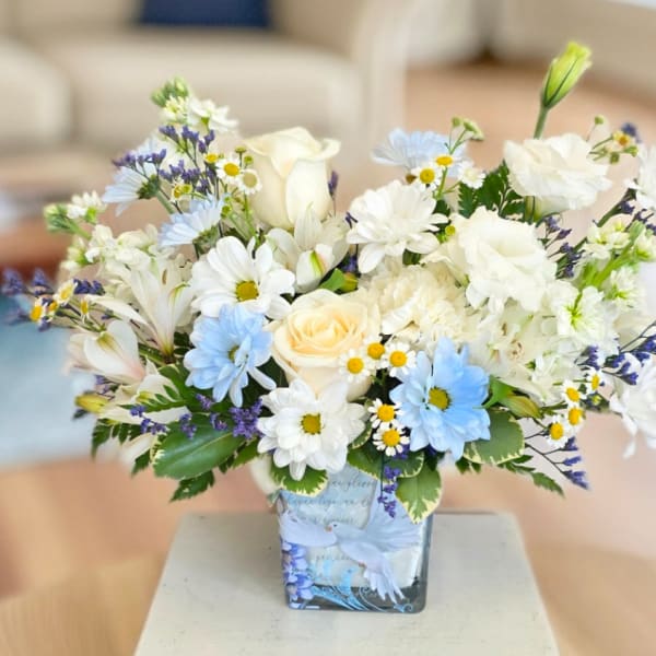 White and blue mixed bouquet in a square glass vase