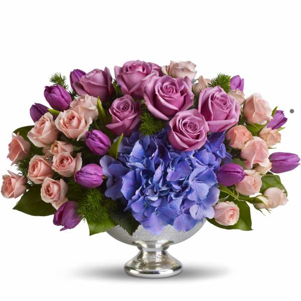 Pink and purple roses with blue hydrangea in a silver pedestal vase