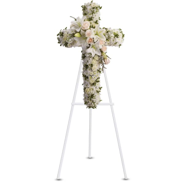White floral cross on a stand with lilies and roses