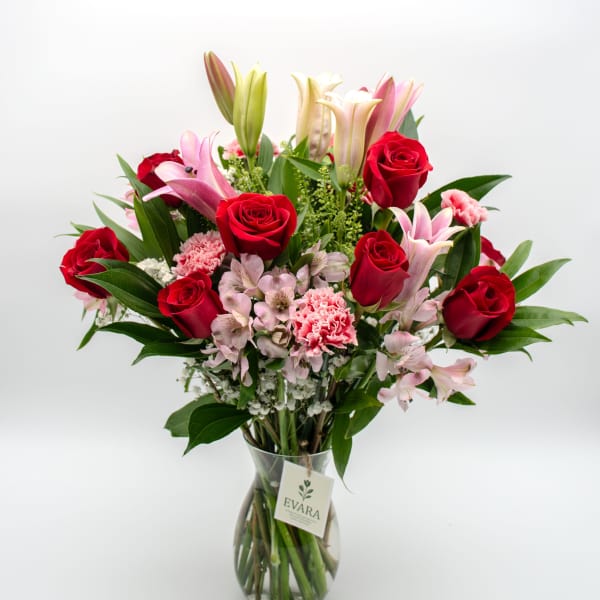 Bouquet of red roses, pink lilies, and carnations in a glass vase