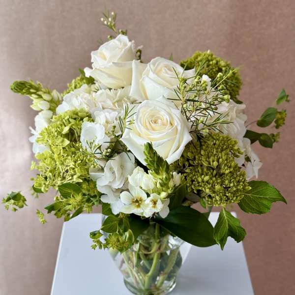 White roses and green hydrangeas in a clear glass vase