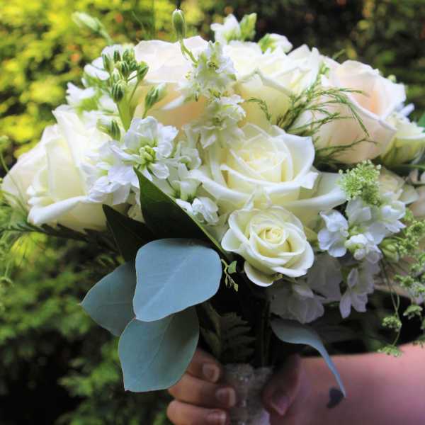 White rose bouquet with small white flowers and blue-green leaves