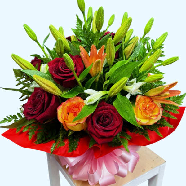 Bouquet of red and orange roses with lilies and a pink ribbon