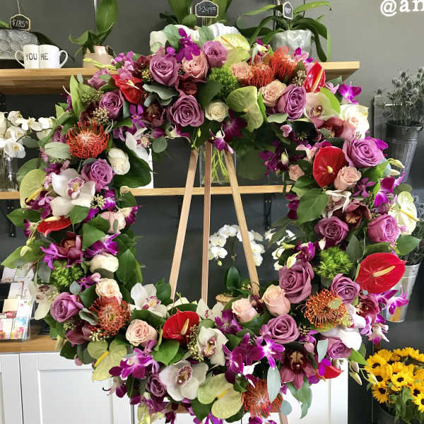 Large floral wreath on a wooden easel with purple, pink, white, and red blooms