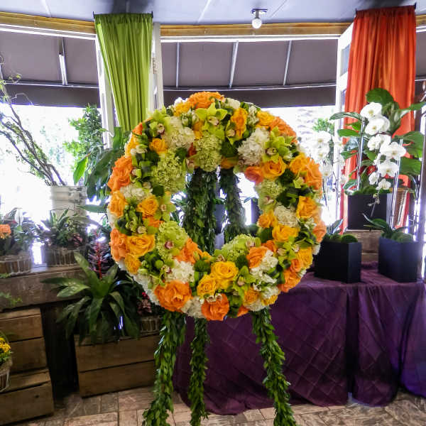 Large floral wreath on a stand with orange, yellow, and white blooms