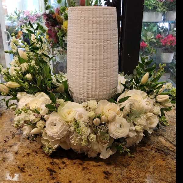 White floral wreath around a tall textured vase