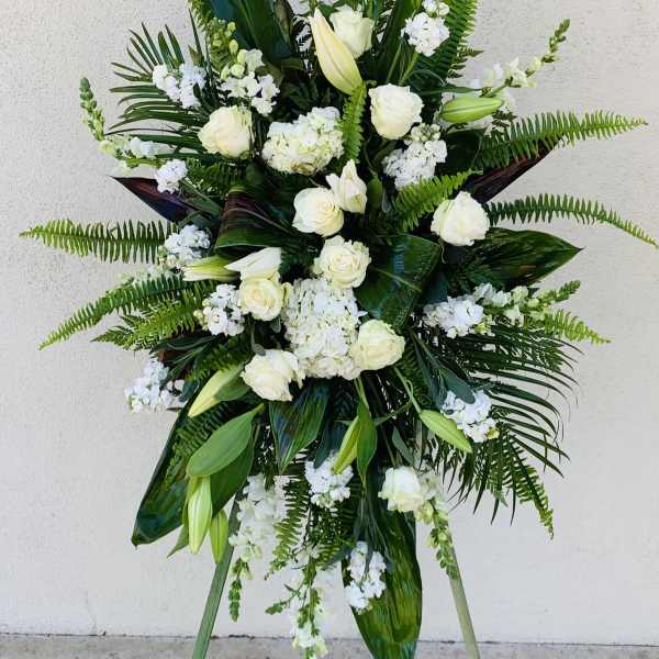 Tall white floral standing spray with roses and lilies on an easel
