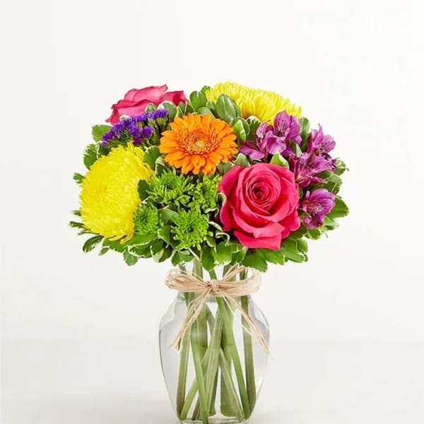 Mixed bouquet of bright flowers in a clear glass vase