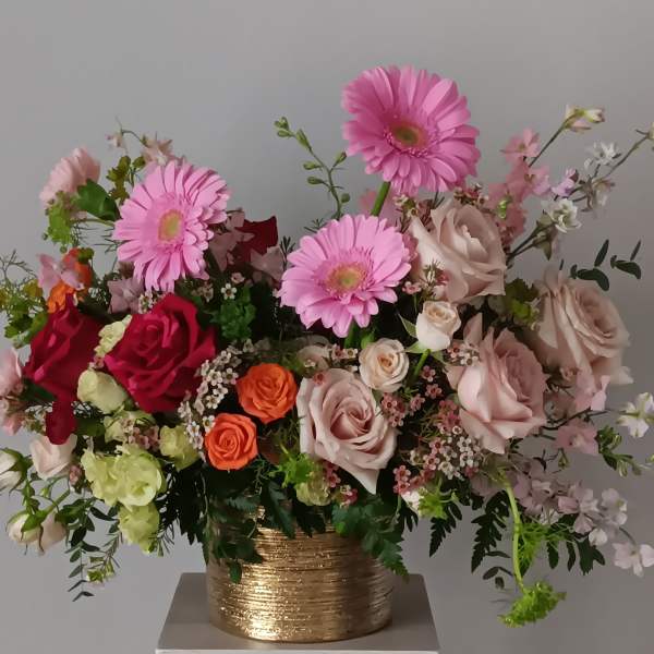 Mixed pink and peach flowers in a gold vase