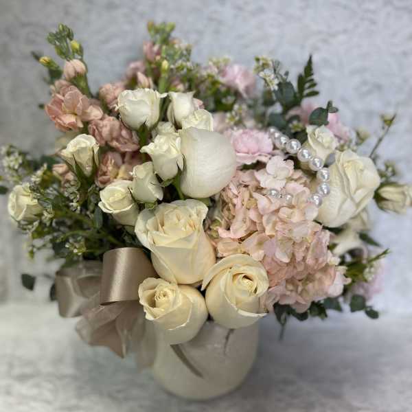 Cream roses and pink hydrangeas in a ribboned vase