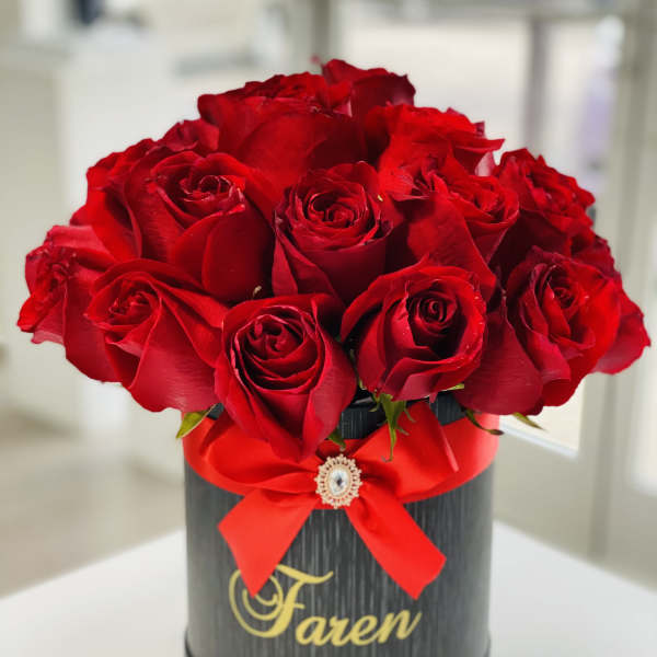 Red roses arranged in a black round box with a red ribbon