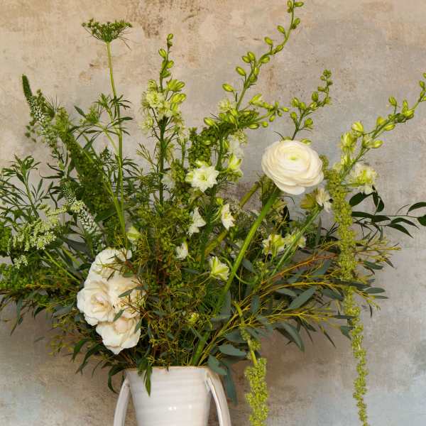 Tall white floral arrangement in a white vase