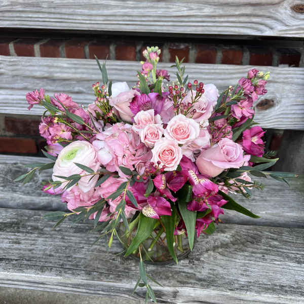 Pink and magenta mixed flower arrangement with roses and hydrangeas in a clear glass vase
