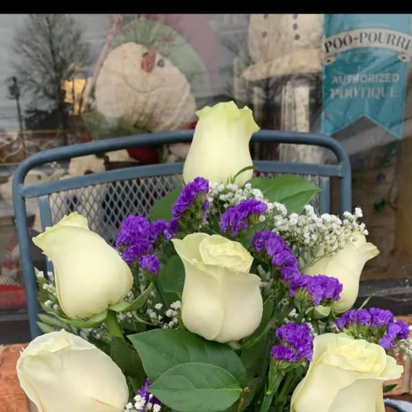 Bouquet of cream roses with purple filler in a glass vase