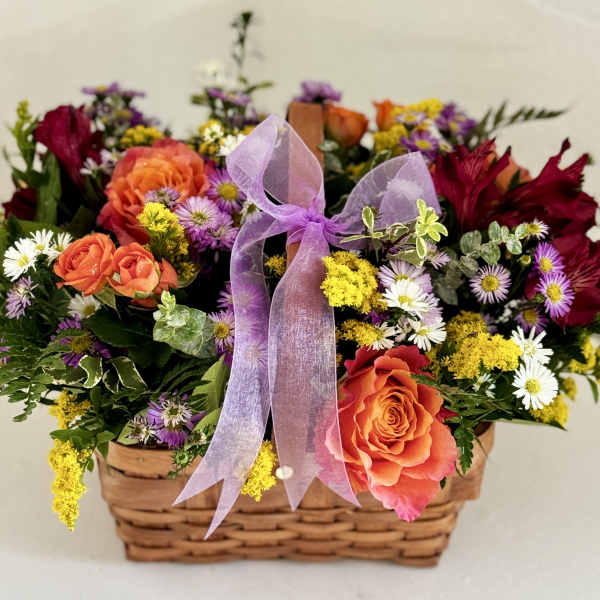 Mixed flower basket with orange roses, daisies, and a purple ribbon