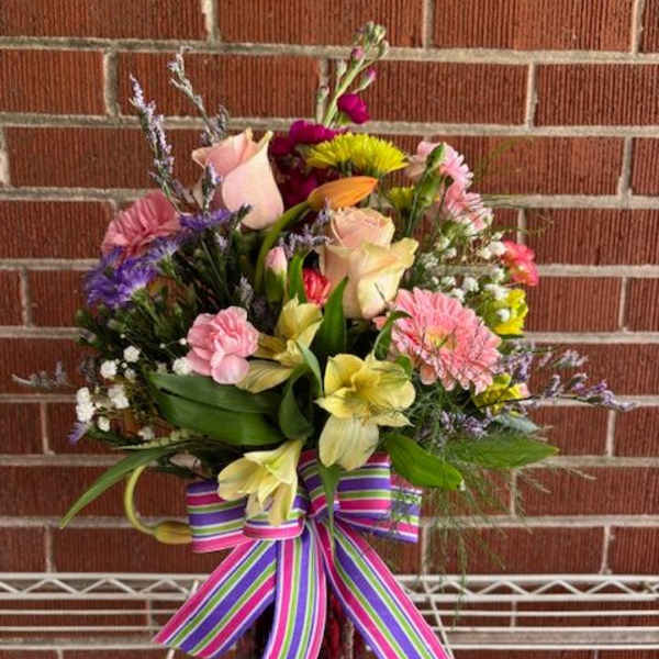 Mixed bouquet in a glass vase with a striped ribbon