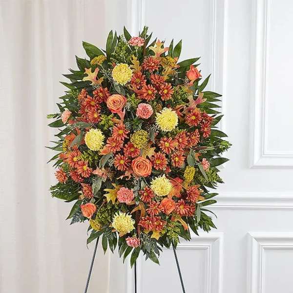 Standing floral wreath with orange and yellow blooms on an easel