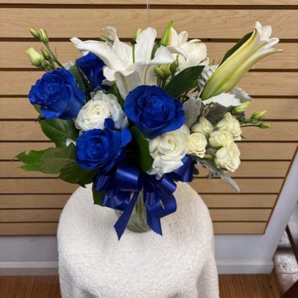 Blue and white bouquet with lilies and roses tied with a blue ribbon