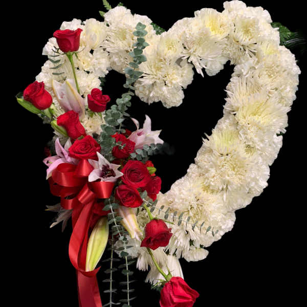 Heart-shaped floral arrangement with white blooms and red roses on a black background