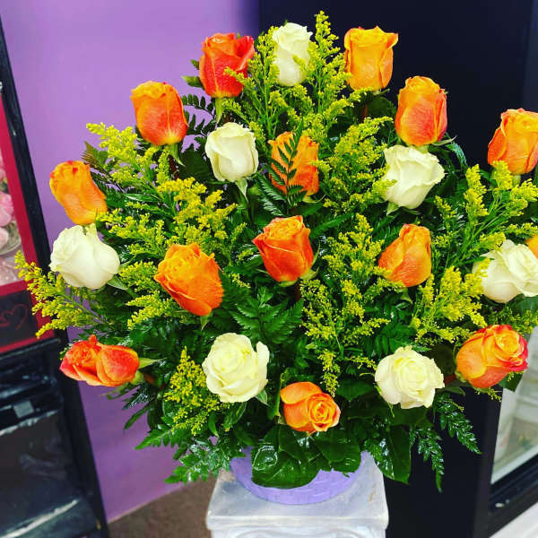 Bouquet of orange and white roses in a lavender container