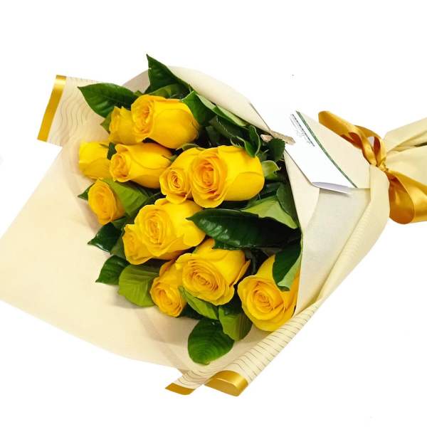 Bouquet of yellow roses wrapped in cream paper with a gold ribbon