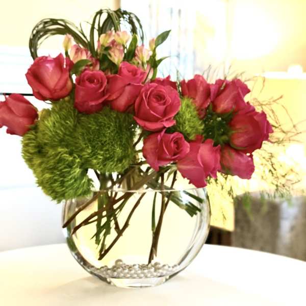 Pink roses in a round glass vase with green pom-pom flowers