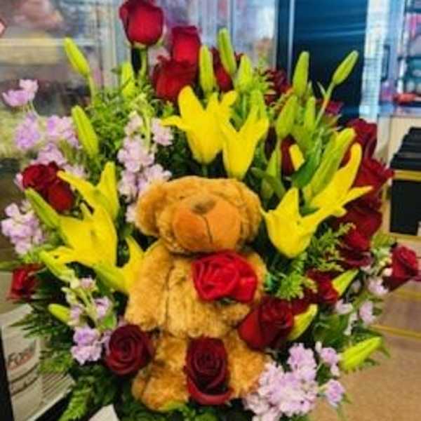 Bouquet of red roses and yellow lilies with a teddy bear