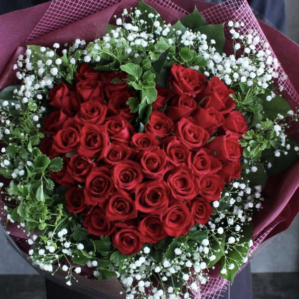 Heart-shaped bouquet of red roses with white baby's breath