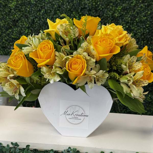 Yellow roses and white alstroemeria in a white heart-shaped box