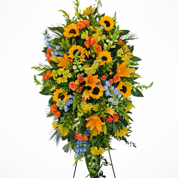 Tall standing floral spray with sunflowers, orange roses, and lilies on a metal easel