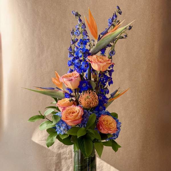 Tall bouquet of orange and pink flowers in a clear glass vase
