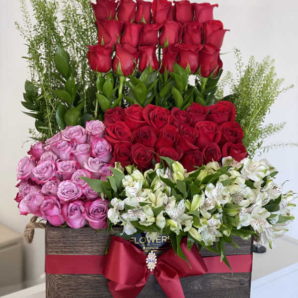Large box arrangement of red, pink, and white roses with greenery