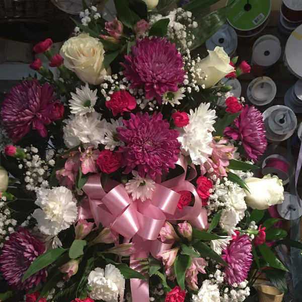 Large bouquet of pink, white, and cream flowers with a pink ribbon
