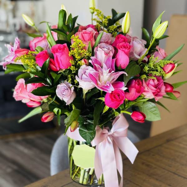 Pink rose bouquet in a clear glass vase with a ribbon