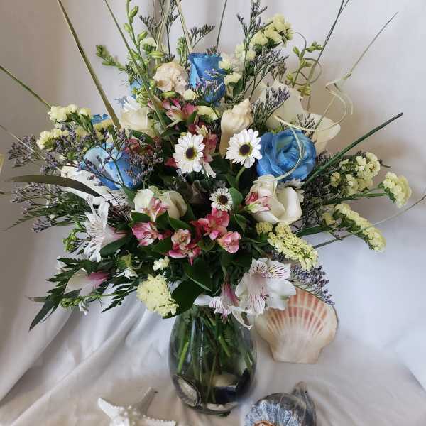 Mixed bouquet in a glass vase with blue, white, and pink flowers