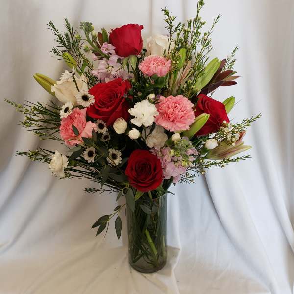 Mixed bouquet of red and pink flowers in a glass vase