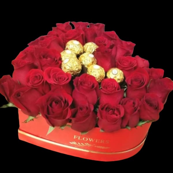 Red roses arranged in a heart-shaped box with gold-wrapped chocolates in the center