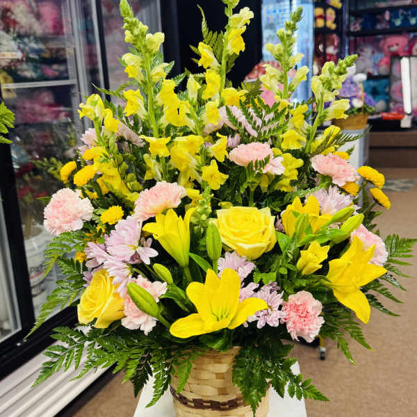 Basket arrangement of yellow lilies, roses, snapdragons, and pink carnations