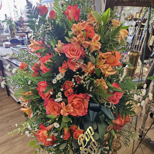 Large standing floral spray with orange roses and alstroemeria on an easel