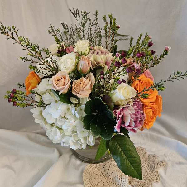 Mixed bouquet of roses, hydrangeas, and carnations in a glass vase