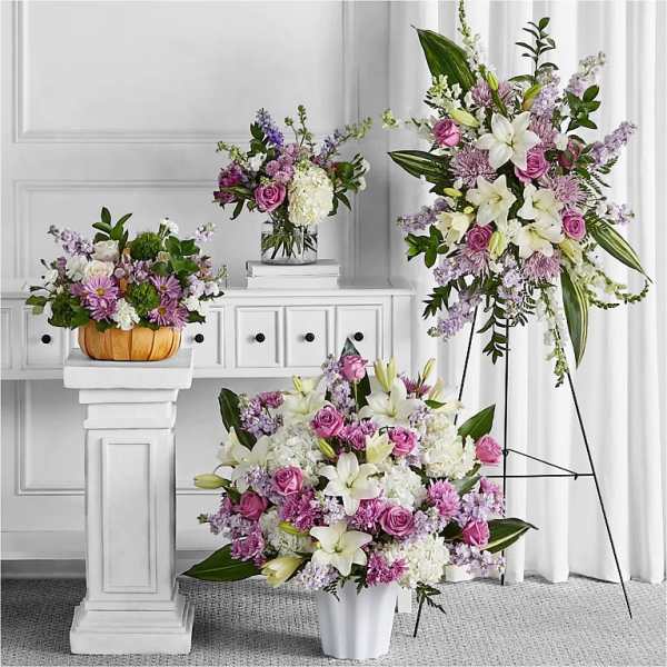 Three floral arrangements with pink and white blooms in vases and a basket