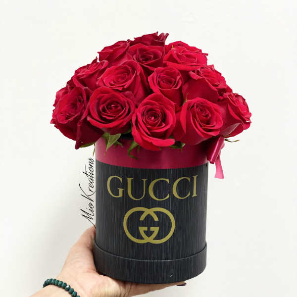 Red roses arranged in a black Gucci hat box