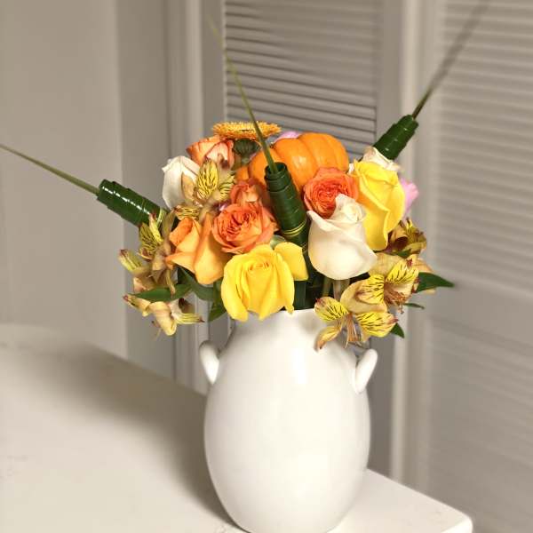 Bouquet of orange, yellow, and white roses in a white vase