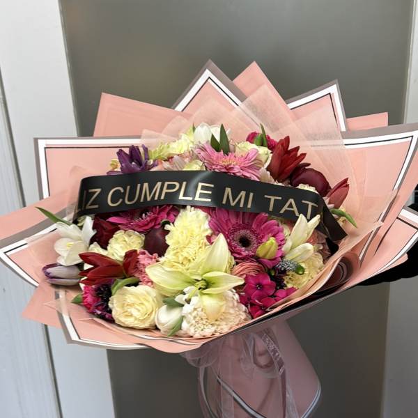 Mixed bouquet of pink, red, white, and yellow flowers wrapped in pink paper